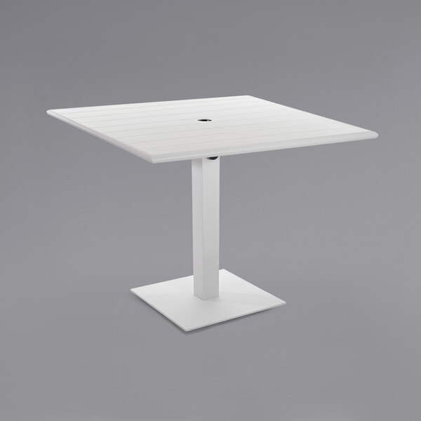 A BFM Seating white square table with a square base and umbrella hole.