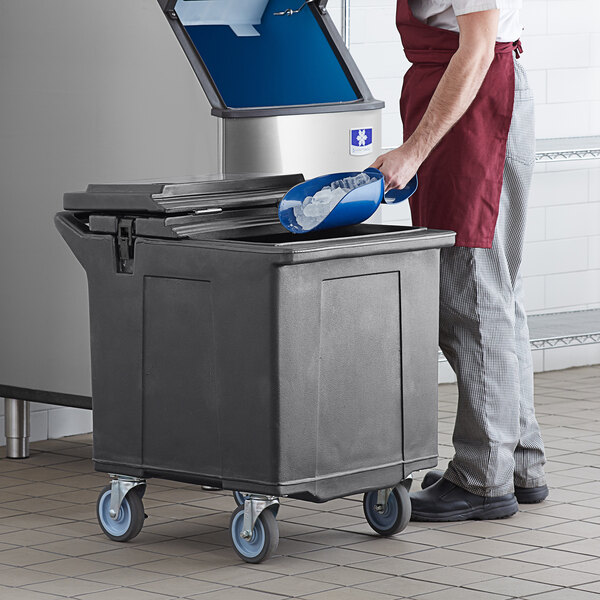 A man in a kitchen using a blue CaterGator mobile ice bin on a counter.