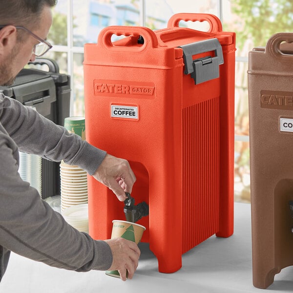A man pouring coffee into a red CaterGator insulated beverage dispenser.