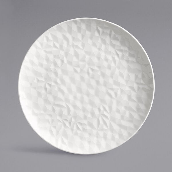 A white porcelain round plate with a textured surface.