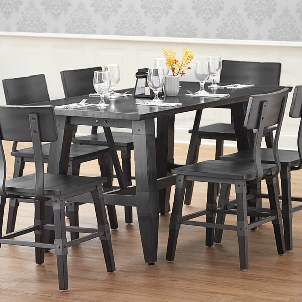 A Lancaster Table & Seating antique slate gray wooden trestle table base with chairs and wine glasses on a restaurant dining table.