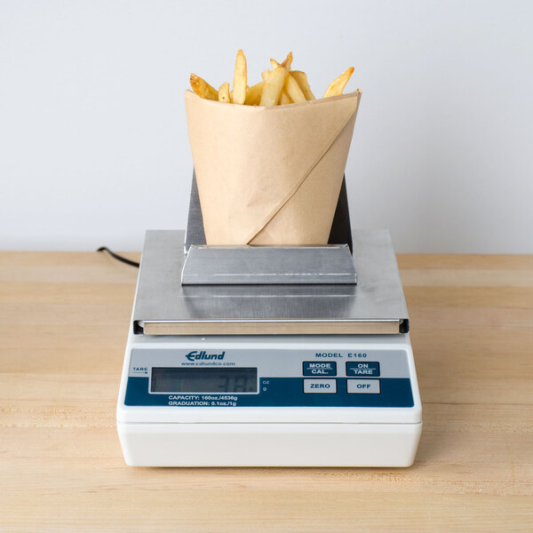 An Edlund digital portion scale with french fries in a paper bag on top.