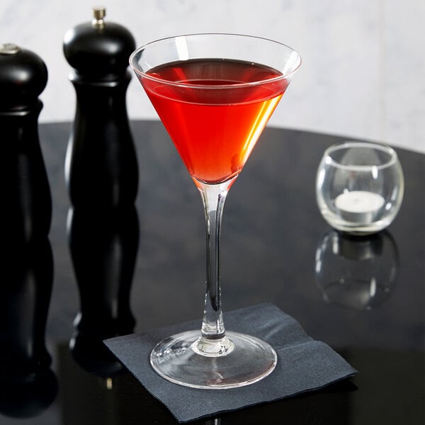 An Anchor Hocking martini glass filled with red liquid on a black table.