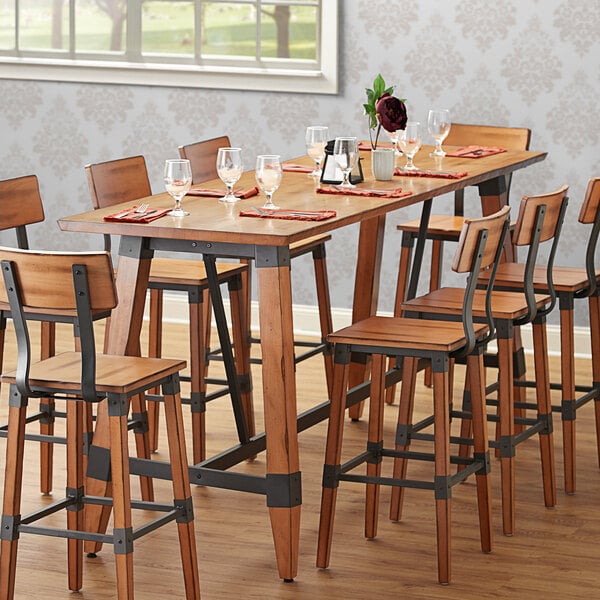 A Lancaster Table & Seating bar height trestle table with chairs and wine glasses.