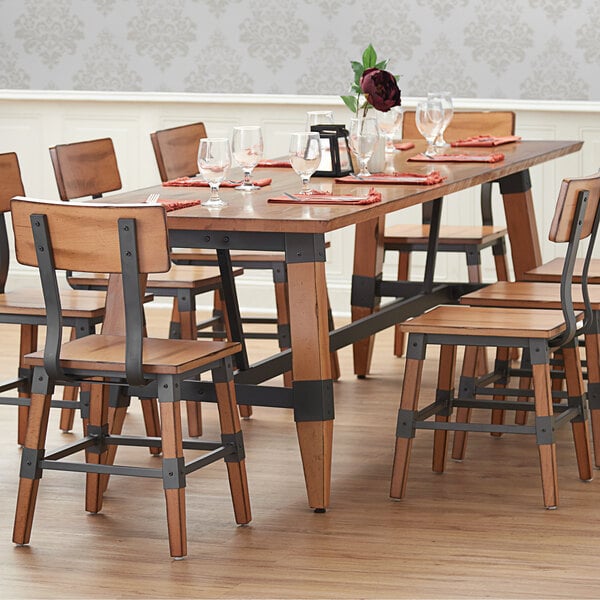 A Lancaster Table & Seating solid wood dining table with wooden trestle legs.