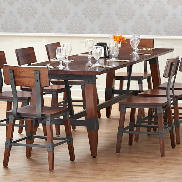A Lancaster Table & Seating solid wood dining table with wine glasses on it.