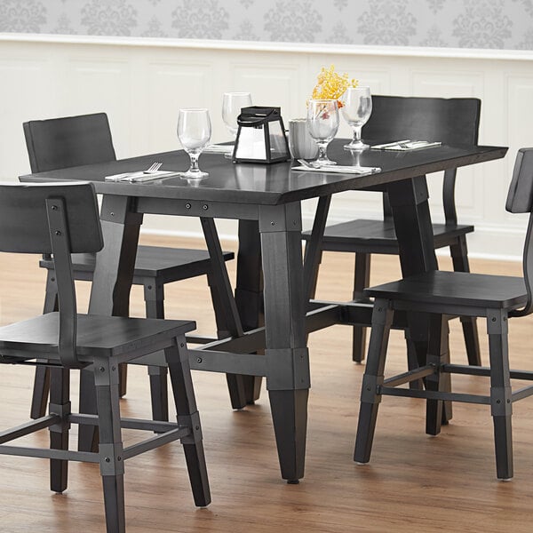 A Lancaster Table & Seating solid wood dining table with a slate gray finish and chairs on a restaurant dining area.