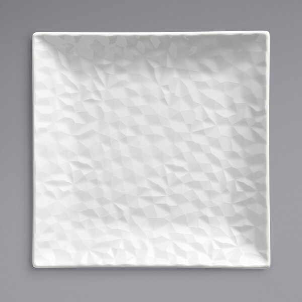A white square plate with a textured surface and triangular pattern.