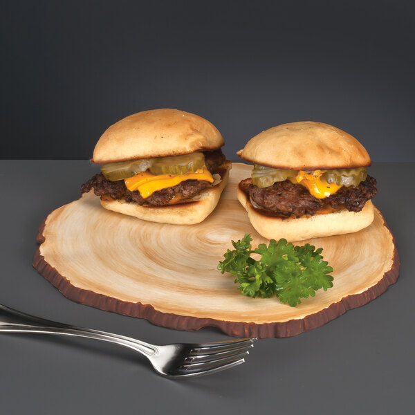 A Libbey faux wood slice porcelain serving board with two cheeseburgers on it.