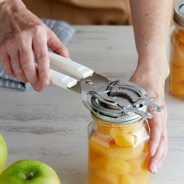 A hand using a Fox Run jar vise to open a jar of canned fruit.