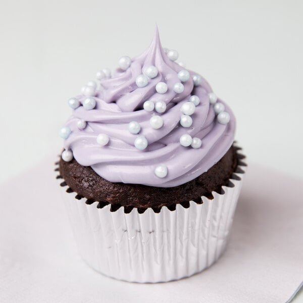 A cupcake in a silver Ateco baking cup with purple frosting and pearls.