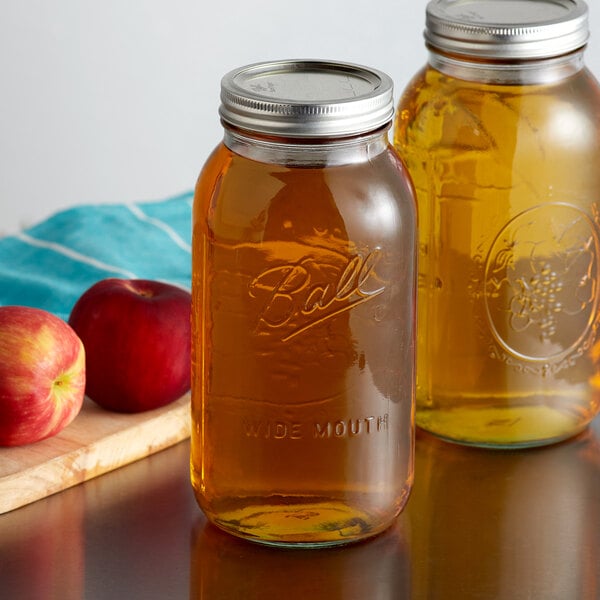 Two jars of canned apple juice next to cutting board with apples