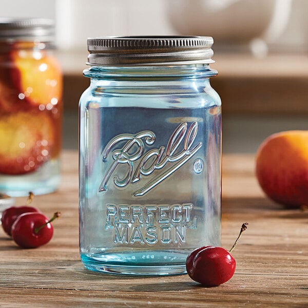 Aqua Ball canning jar on table with cherries, a peach, and jar of canned peach slices
