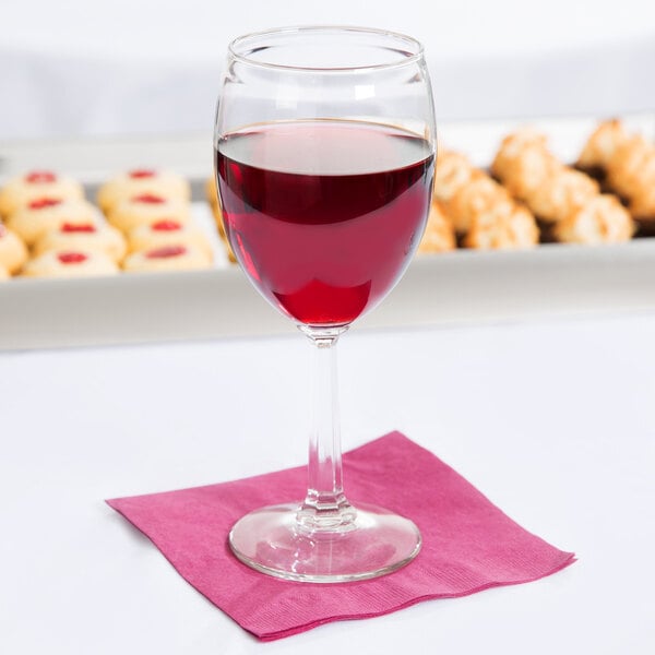 A Libbey Napa Country goblet filled with red wine on a pink napkin.