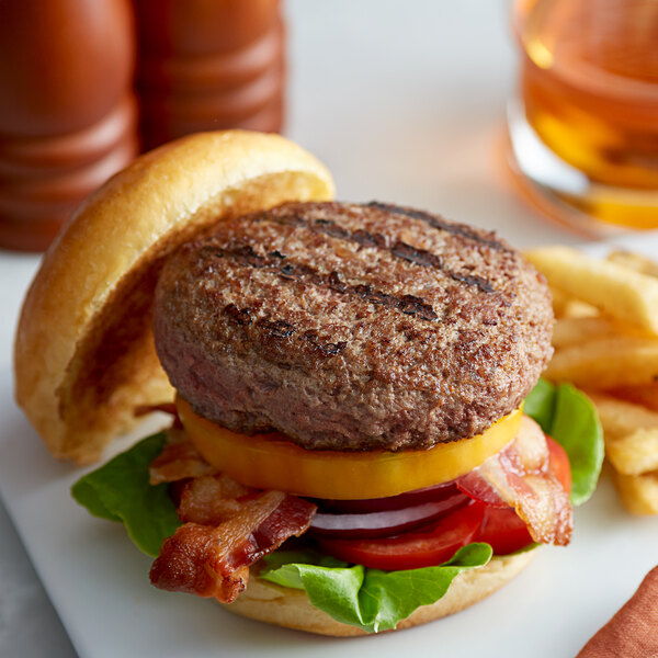 A close up of a burger with bacon, lettuce, and tomatoes.
