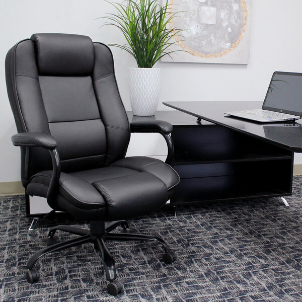 A Boss black leather office chair next to a desk with a laptop on it.