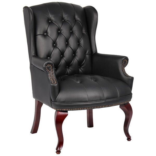 A black leather Boss wingback guest chair with tufted back and brown legs.