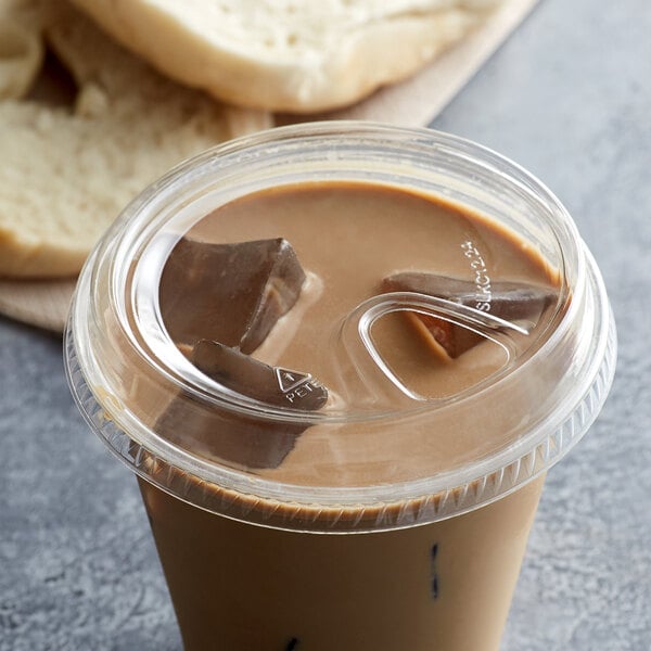 A clear plastic cup of coffee with ice cubes and a brown liquid with a Fabri-Kal clear plastic sip lid on it.