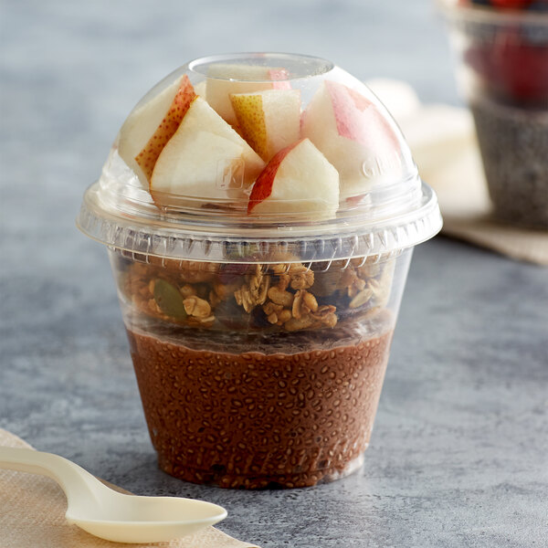 A Fabri-Kal clear plastic parfait cup with fruit in it and a spoon.