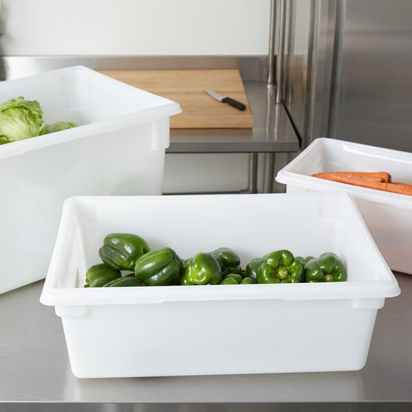 A white Rubbermaid food storage box on a kitchen counter filled with green peppers.