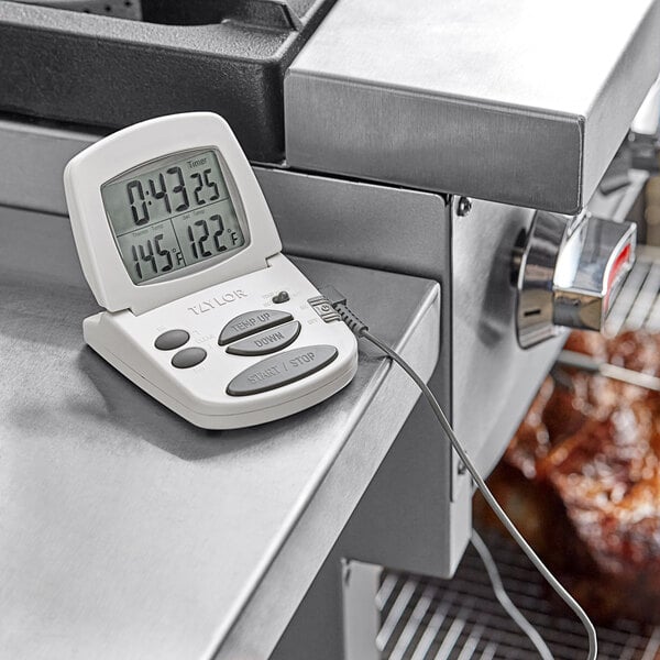 A white Taylor digital cooking thermometer on a counter.