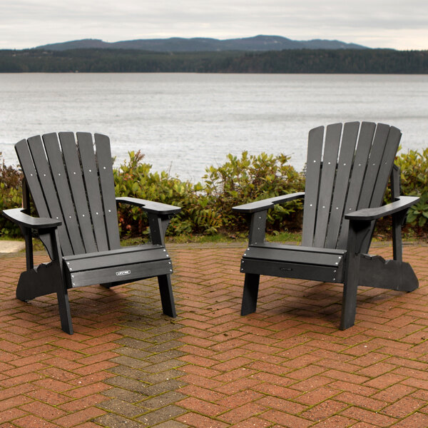 Two black Lifetime Adirondack chairs on a brick patio.