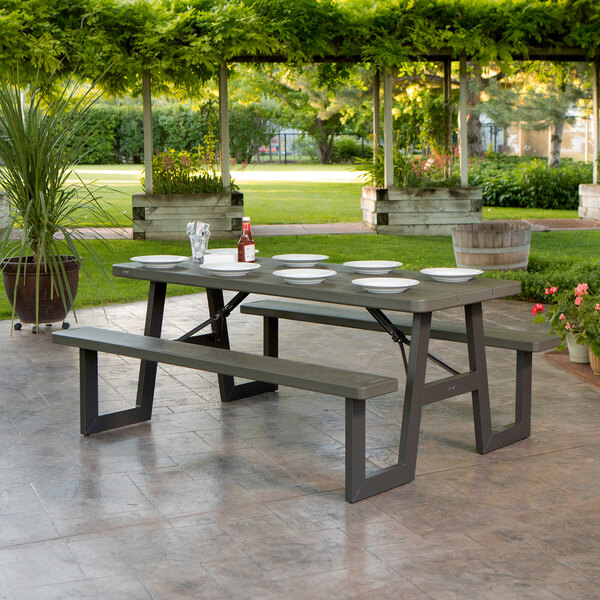 A brown Lifetime rectangular plastic picnic table with attached benches and plates on it.