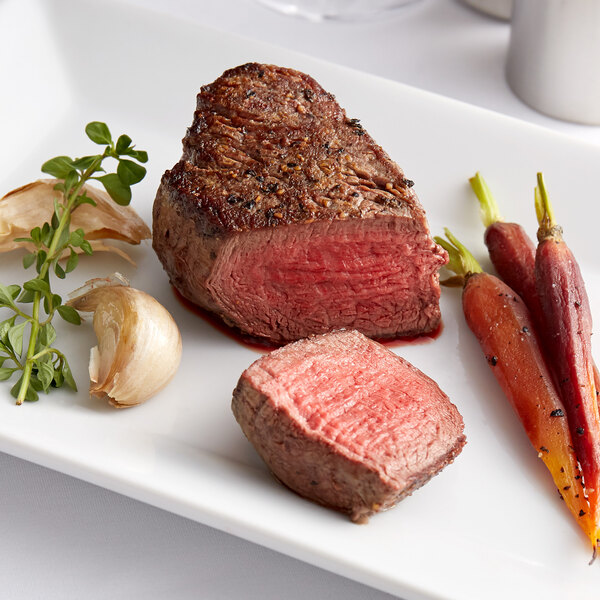 A Warrington Farm Meats filet mignon steak on a plate with vegetables.