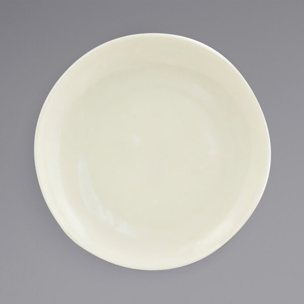 A Front of the House vanilla bean porcelain plate with a small rim on a gray surface.