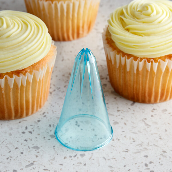 Three cupcakes piped with star-shaped frosting and a plastic cone on a counter.
