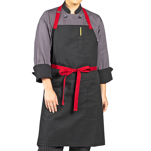 A woman wearing a black Uncommon Chef Rebel apron with red trim.