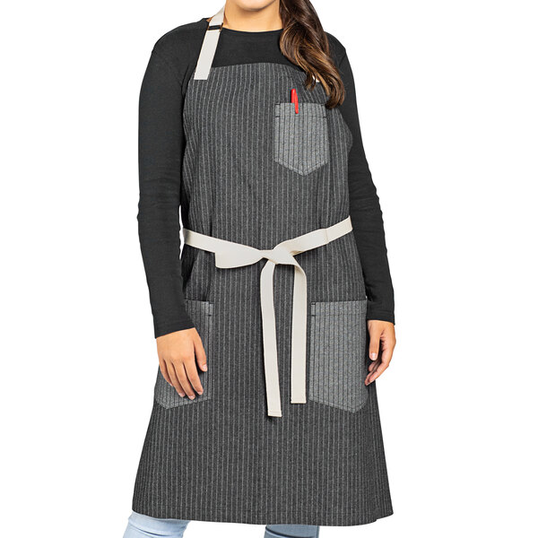 A woman wearing a black and white pinstripe Uncommon Chef bib apron.