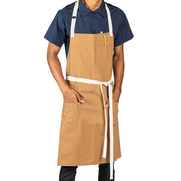 A man wearing a tan Uncommon Chef Rebel apron with natural webbing.