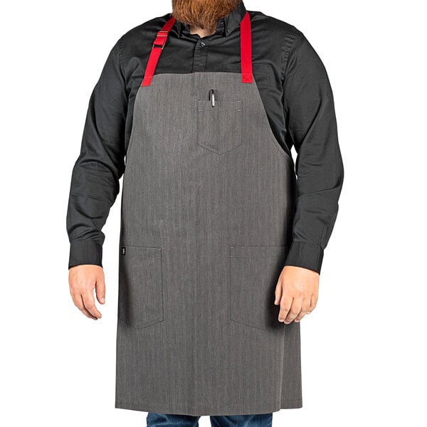 A man with a beard wearing a gray Uncommon Chef apron with red webbing.