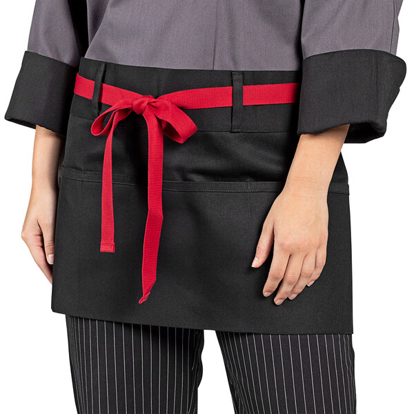 A woman wearing a black Uncommon Chef waist apron with red webbing and pockets.