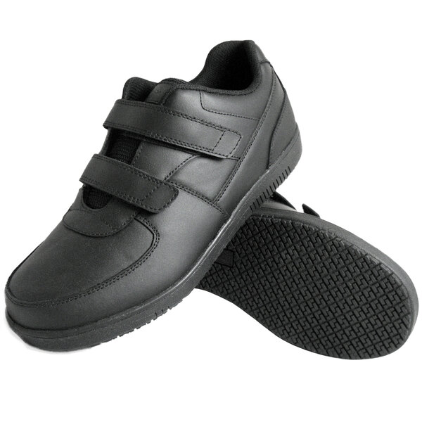 A pair of black Genuine Grip leather shoes with velcro straps.