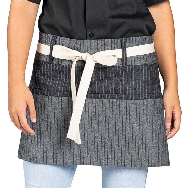 A woman wearing a black and white pinstripe waist apron with natural webbing.
