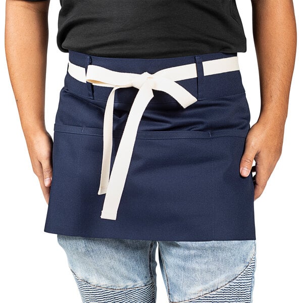A man wearing a Uncommon Chef navy blue apron with a white belt.
