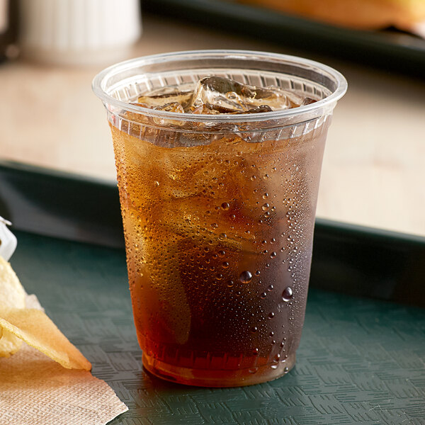 A plastic cup of ice tea with a straw on a tray.