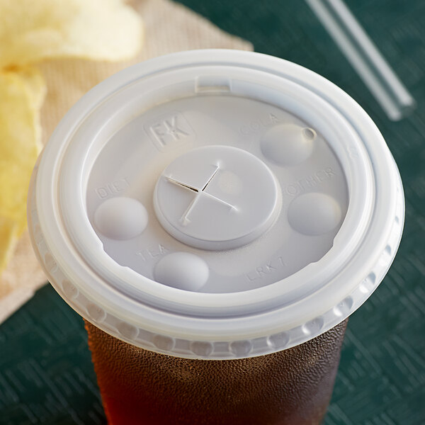 A Fabri-Kal translucent plastic cup with a white lid on a table.