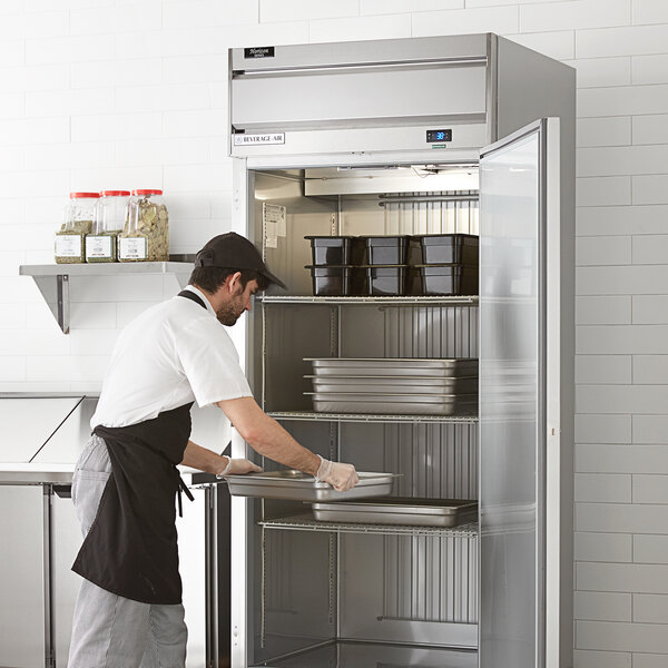 A man in a white apron opening a Beverage-Air Horizon Series reach-in refrigerator in a professional kitchen.