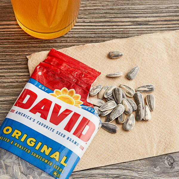 A case of 144 David Roasted Salted Whole Sunflower Seed pouches on a table with a glass of beer.