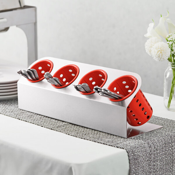 A Steril-Sil stainless steel flatware organizer with red perforated plastic cylinders holding silverware.