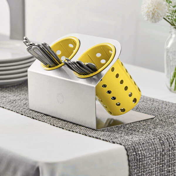 A Steril-Sil stainless steel flatware organizer with yellow perforated plastic cylinders holding silverware.