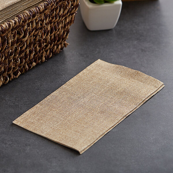 A basket of Hoffmaster FashnPoint burlap print guest towels on a table.