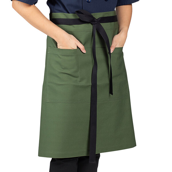 A woman wearing a Uncommon Chef sea green canvas waist apron with black ties.