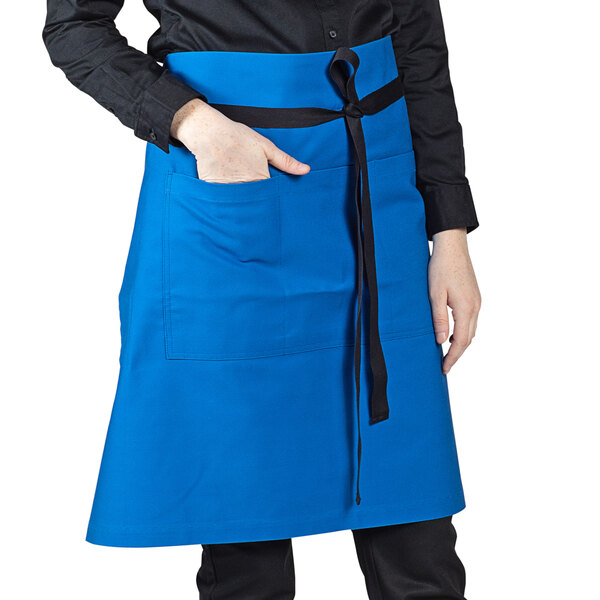 A woman wearing a blue Uncommon Chef waist apron with black ties.