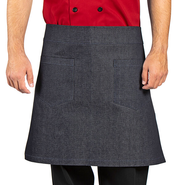 A man wearing a Uncommon Chef denim waist apron with black webbing and pockets.
