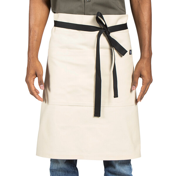 A man wearing a Uncommon Chef ivory apron with black trim.