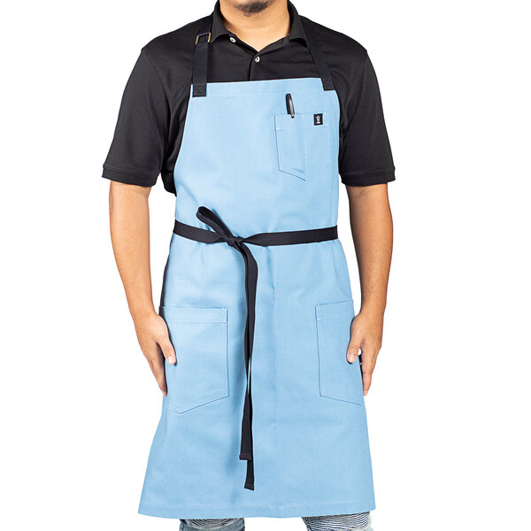 A man wearing a blue Uncommon Chef apron with black webbing.